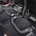 Interior view of two black quick-release brackets with protective foam covers securely mounted to a vehicle's rear seat floor.